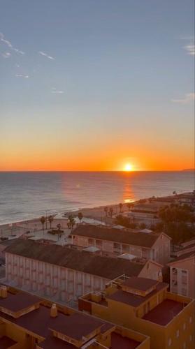 a sunset over a beach with buildings and the ocean at Horizonte al Mar in Miramar