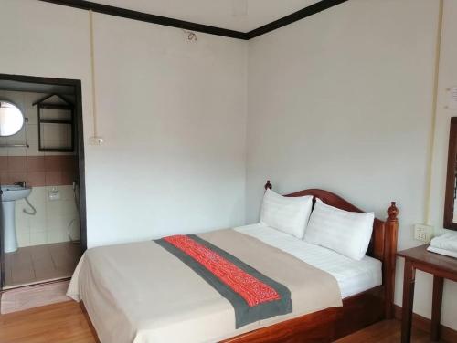 a bedroom with a bed and a bathroom with a sink at DP Guest-house in Pakbeng