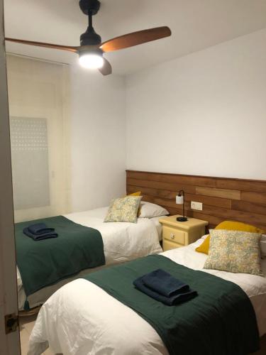ein Schlafzimmer mit zwei Betten und einem Deckenventilator in der Unterkunft Apartament amb terrassa i parking in Llança