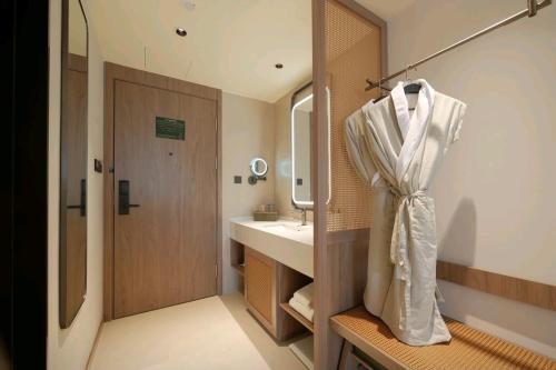 a bathroom with a sink and a robe hanging on a wall at Lijiang Gucheng District RIM Hotel in Lijiang
