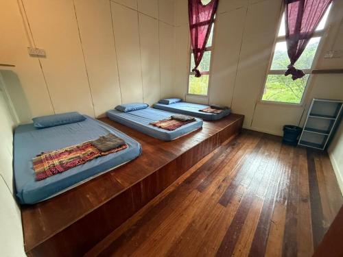 2 Betten in einem Zimmer mit Holzböden und Fenstern in der Unterkunft Mahua Lodge and Campsite in Tambunan