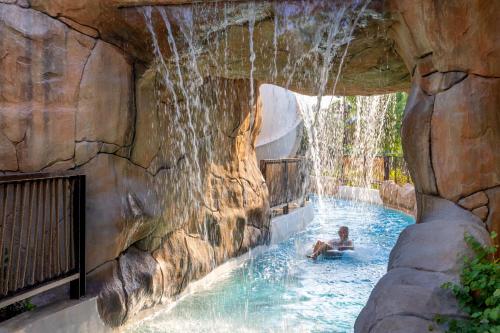 a person in a swimming pool with a waterfall at Grand Hyatt Dubai Resort & Waterpark in Dubai