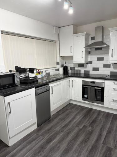 an empty kitchen with white cabinets and appliances at Belexsia Guest House in Stoke on Trent