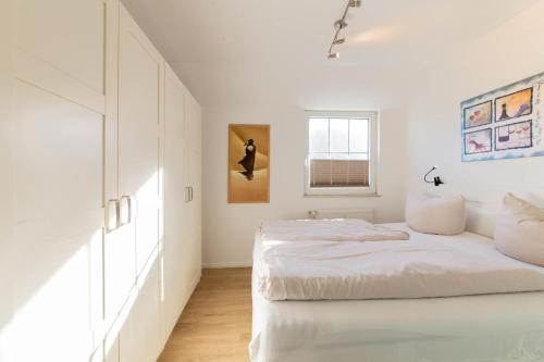 une chambre blanche avec un lit et une fenêtre dans l'établissement Ferienwohnung Ostseerauschen 2, à Scharbeutz