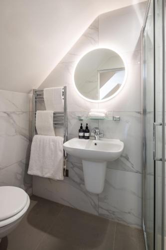 a white bathroom with a sink and a mirror at La Croix Guest House in Isle of Jersey