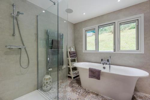 a bathroom with a tub and a glass shower at 4 Bed in Aberdovey oc-p33131 in Scyborycoed