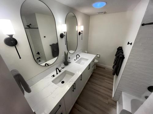 ein weißes Badezimmer mit zwei Waschbecken und zwei Spiegeln in der Unterkunft Camelia Home in Kelowna