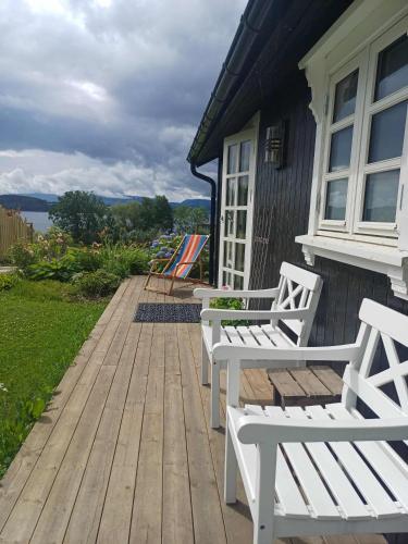 two white benches sitting on a wooden deck at Lovely tiny house with a dream view ! in Østdal