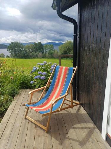 a deck chair sitting on a porch at Lovely tiny house with a dream view ! in Østdal