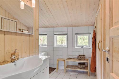 uma casa de banho com uma banheira, uma mesa e janelas em JB827-Fjerritslev-Revlingestien-93 em Torup Strand