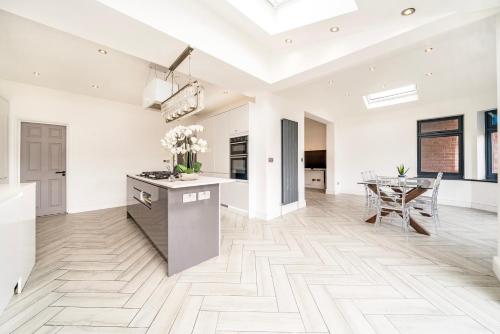 Una cocina y comedor con paredes blancas y pisos de madera. en Juliet balcony room, en Lower Sydenham Station