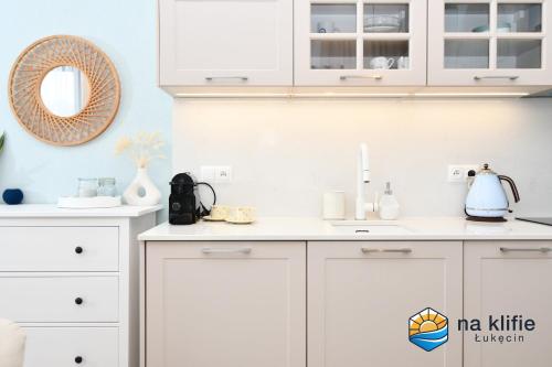 a kitchen with white cabinets and a sink at Apartament na klifie - Łukęcin in Łukęcin