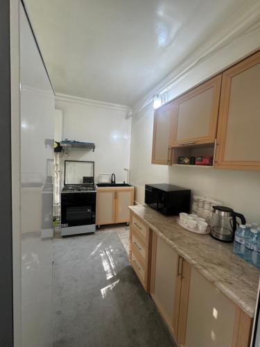 une cuisine avec des armoires en bois et un appareil noir dans l'établissement Registan 15 min walk away, à Samarcande