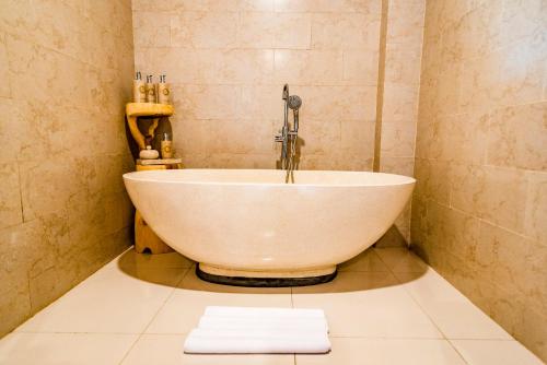 a bath tub in a bathroom with a sink at Ellena Resort Tegallalang by Dhananjaya Hospitality in Tampaksiring