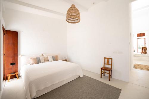 a white bedroom with a bed and a chair at Monte de Torquines - Casa de Campo com piscina em Odemira in Odemira