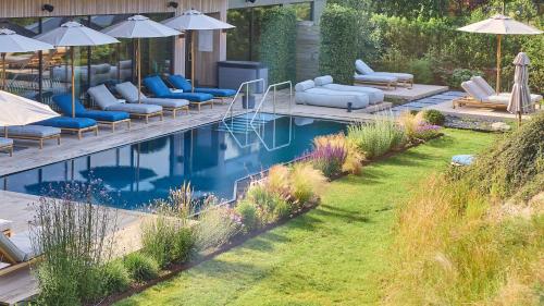 a pool with lounge chairs and umbrellas in a yard at Thöles Hotel Bücken in Bücken