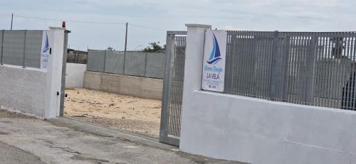 a fence with a gate with a sign on it at Home Design La Vela in Zapponeta