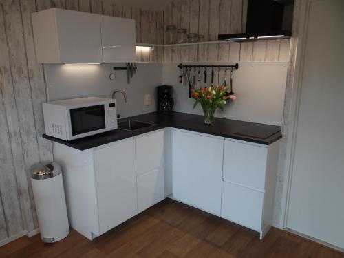 a kitchen with white cabinets and a microwave at Holidayhouse Akkerrand Kamperland in Kamperland