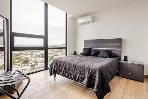 a bedroom with a large bed and large windows at Moderno Depa a 3 mins de Fundidora y Tec de Mty in Monterrey