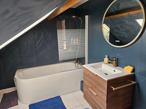 a bathroom with a tub and a sink and a mirror at Maison Sérénité in Lailly-en-Val