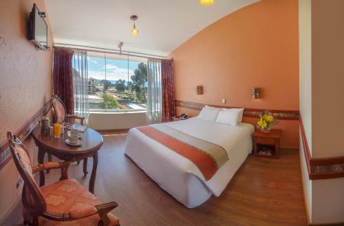 a bedroom with a bed and a table and a window at Taypikala Lago in Puno