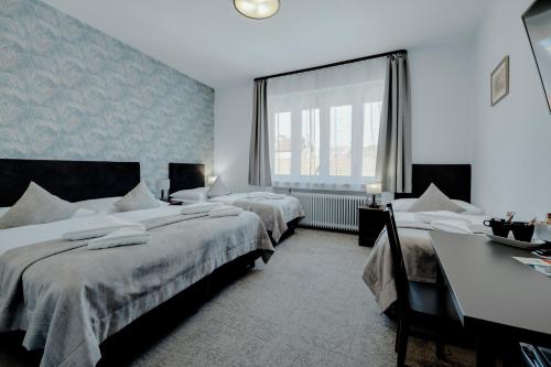 um quarto com duas camas, uma escrivaninha e uma janela em 7Days B&B em Bratislava