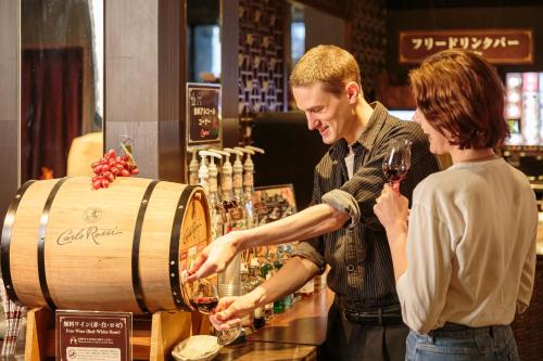 a man and a woman pouring wine into a wine barrel at Hotel Balian Resort Higashi Shinjuku in Tokyo
