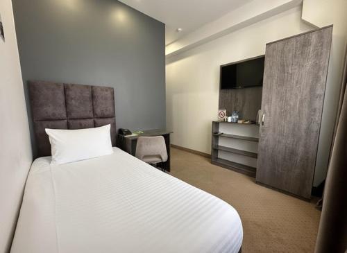 a bedroom with a bed and a desk and a television at Median Hotel, City Center Yerevan in Yerevan