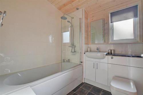 a bathroom with a tub and a toilet and a sink at Milliners Lodge in Kelling