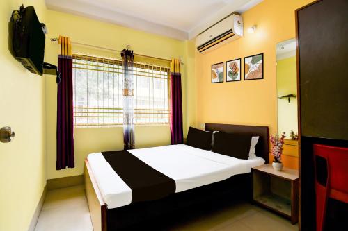 een slaapkamer met een bed en een raam bij Hotel O Ankita Lodge in Siliguri