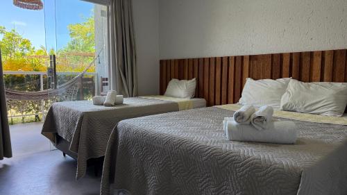 a hotel room with two beds with towels on them at Pousada Pé na Areia in São Miguel dos Milagres