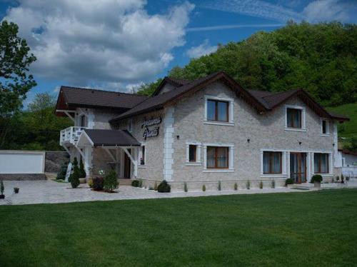 una gran casa de piedra con un patio de césped en Pensiunea Graniti, en Lunca