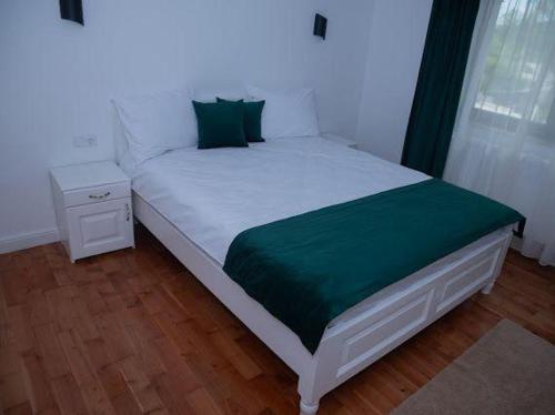 a bedroom with a bed with a green blanket at Pensiunea Graniti in Lunca