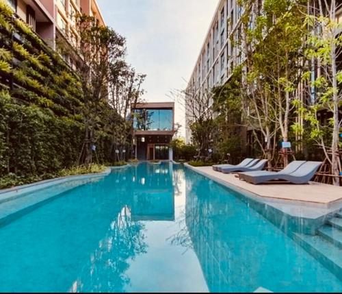 a swimming pool with chairs and a building at The Central Escape Phuket in Ban Rangeng