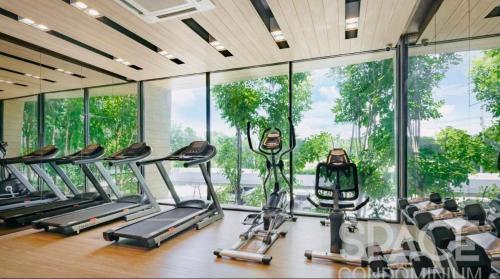 a gym with several cardio machines in a room with windows at The Central Escape Phuket in Ban Rangeng
