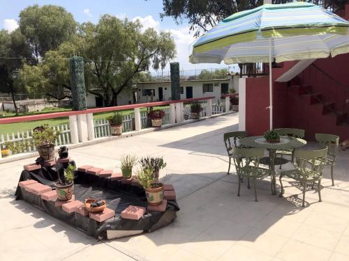 a patio with a table and chairs and an umbrella at Rancho el Andariego and La Catrina 