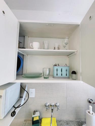 eine Küche mit weißen Regalen mit Schalen und Geschirr in der Unterkunft Monoambiente y sala de estar con garage in Mar del Plata