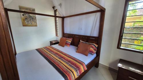 Safina Cottages في شاطئ دياني: غرفة نوم صغيرة بسرير مع اطار خشبي