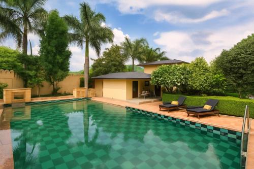 una piscina con dos sillas y una casa en KP Group of Hotel - RAM BAGH Udaipur, en Udaipur