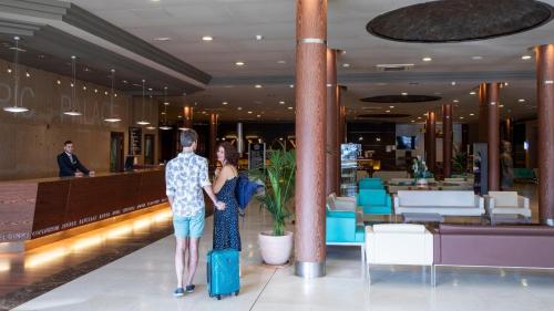 Un hombre y una mujer de pie en el vestíbulo de un hotel en Evenia Olympic Palace, en Lloret de Mar