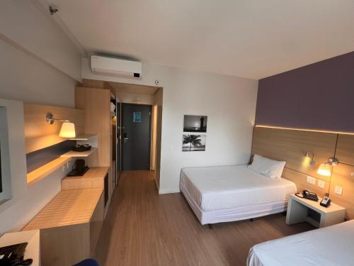 a hotel room with a bed and a desk at Flats na praia com AC, piscina, sauna e academia! in Santos