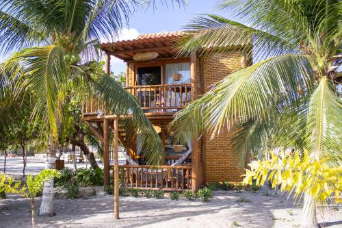 a house on the beach with palm trees in front of it at Sitio Meu Refúgio Paracuru in Paracuru