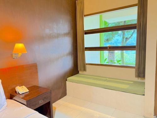 a bedroom with a window and a phone on a table at De View Hotel By PRO in Punten