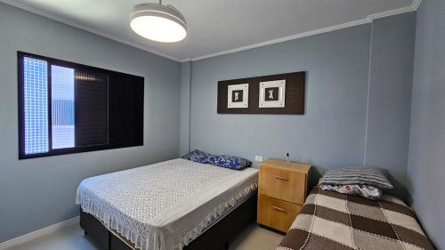 a bedroom with a bed and a dresser and a window at Apartamento com 1 suíte, 1 lavabo, 1 vaga a 70m da Praia in Praia Grande