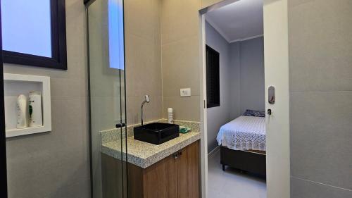 a bathroom with a sink and a shower with a bed at Apartamento com 1 suíte, 1 lavabo, 1 vaga a 70m da Praia in Praia Grande