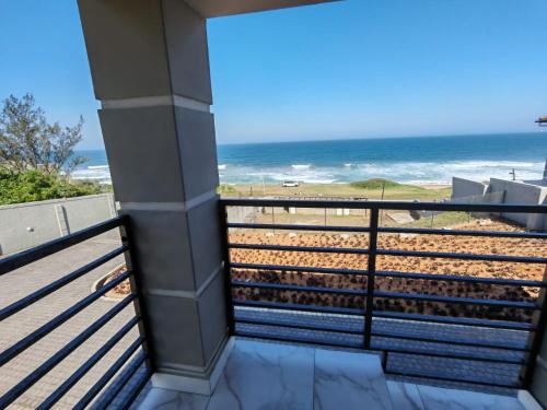 a balcony with a view of the beach at Modern Beachfront Escape in La Mercy in La Mercy