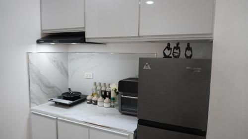 a kitchen with a black refrigerator and white cabinets at 1BR with Pool at One Pontefino Tower, Batangas City in Batangas City