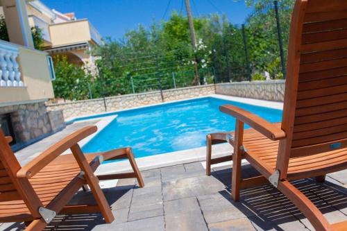 ein Pool mit zwei Holzstühlen daneben in der Unterkunft Studio für 2 Personen  2 Kinder ca 60 qm in Šilo, Kvarner Bucht Krk in Šilo