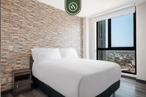 a bedroom with a white bed and a brick wall at 1BR Condo in Polanco - Pool - Coworking - CityView in Mexico City