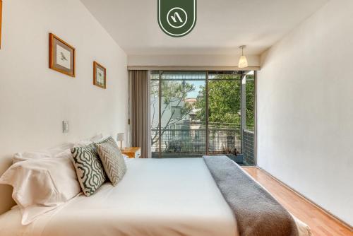 a bedroom with a bed and a large window at Centric 2 BR Condo - Roma - Rio de Janeiro Park in Mexico City